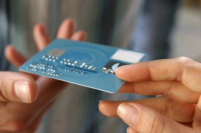 Photo of someone handing a credit card over to pay with it